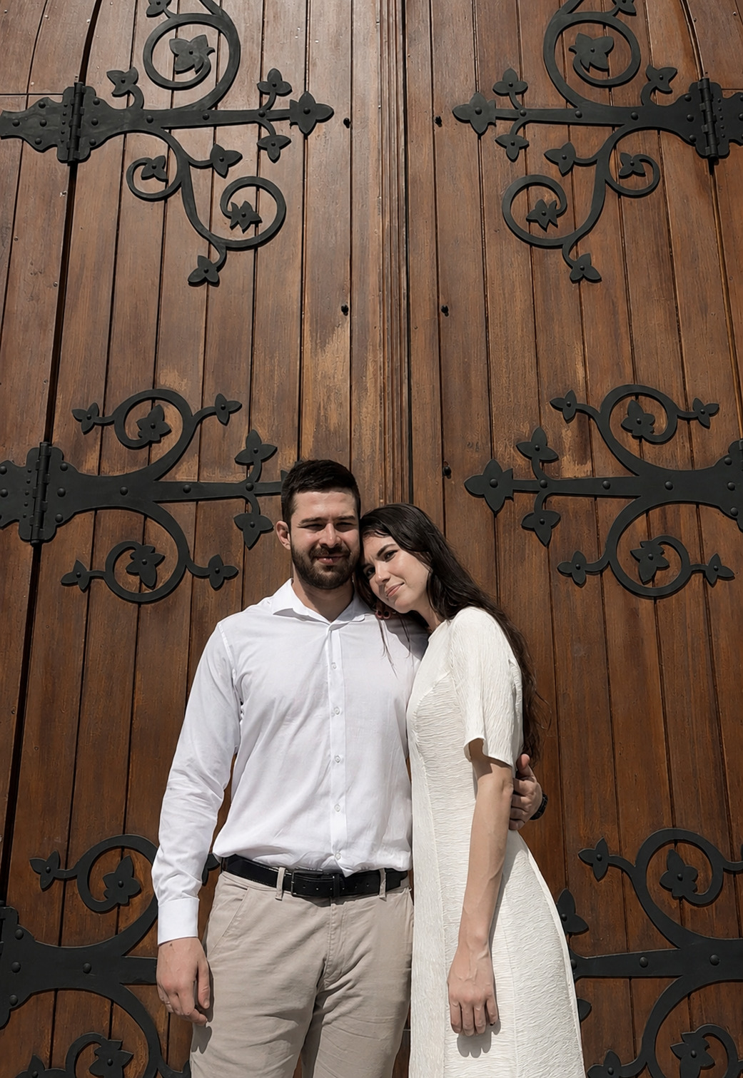 Pedro e Julia abraçados ao pôr do sol, com palmeiras e buganvílias ao fundo